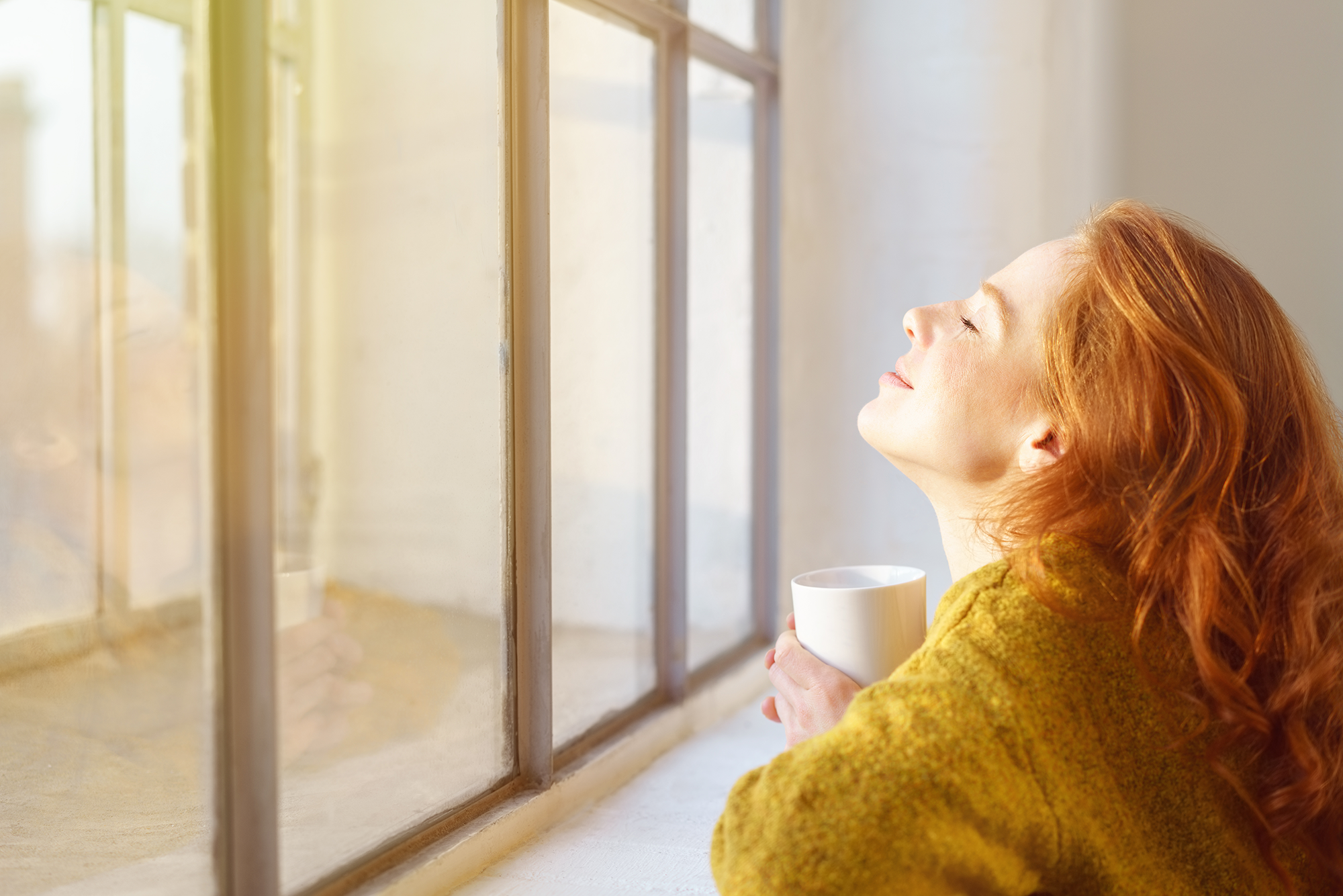 Eine Frau genießt ihren Tee am Fenster.