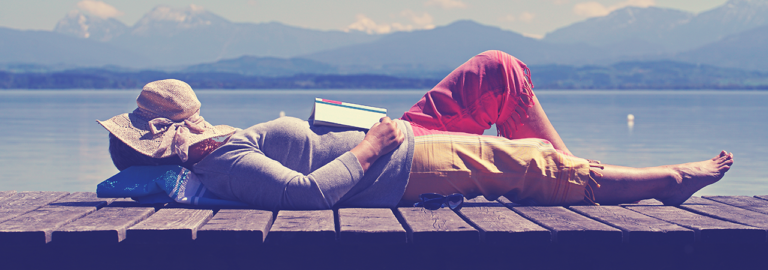 Frau entspannt am See mit Buch.