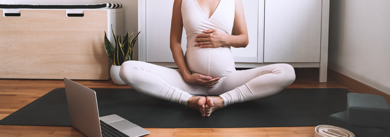 Schwangere Frau meditiert und hält ihren Babybauch.