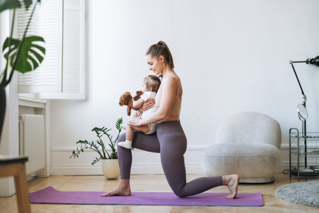 Eine junge Frau macht Fitness mit ihrem Baby in den Armen.